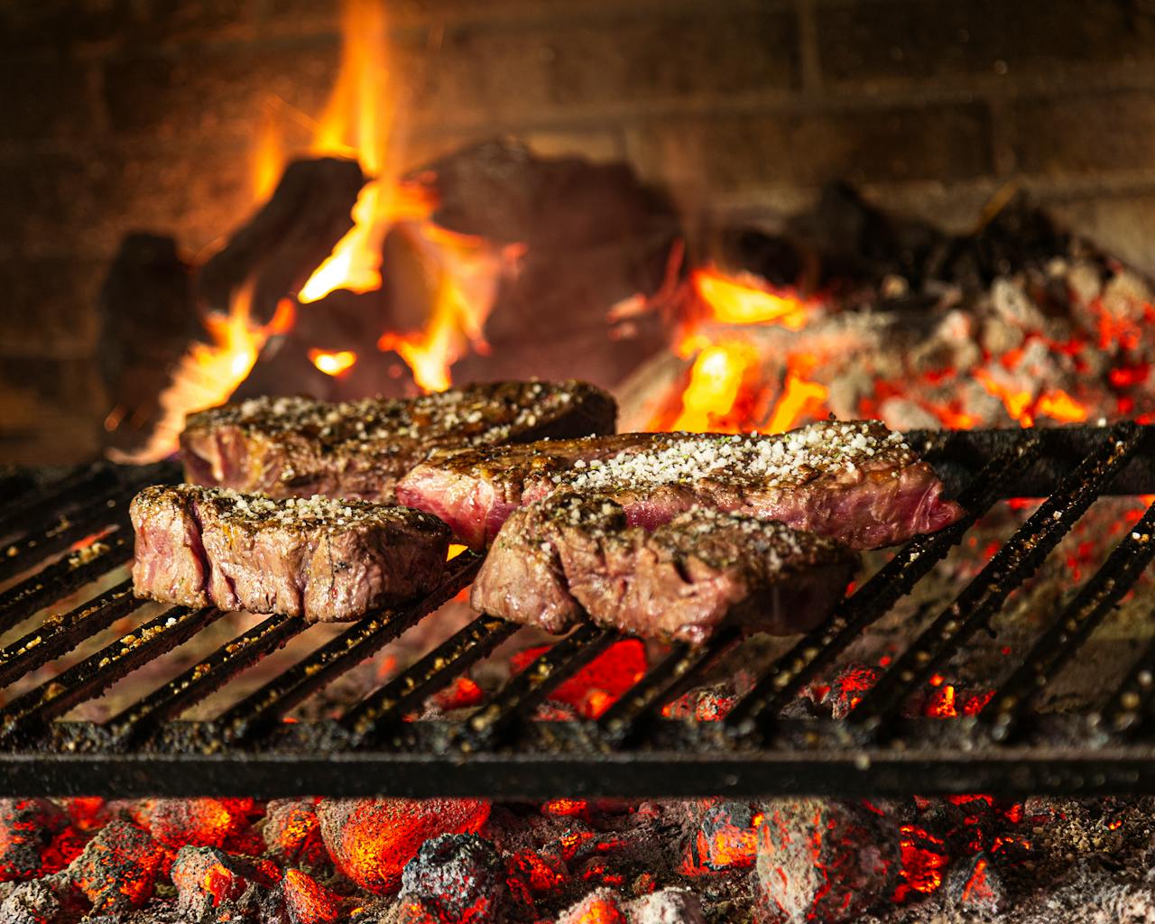 Succulent steaks grilling over hot coals and flames for a mouthwatering cookout.